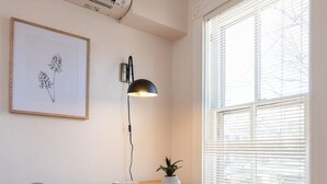 A dining area with a wooden table, clear plastic chairs, a potted plant, and a framed botanical illustration on the wall. - Retro Apartment | Furnished Monthly Rental in Belmont (Charlottesville)