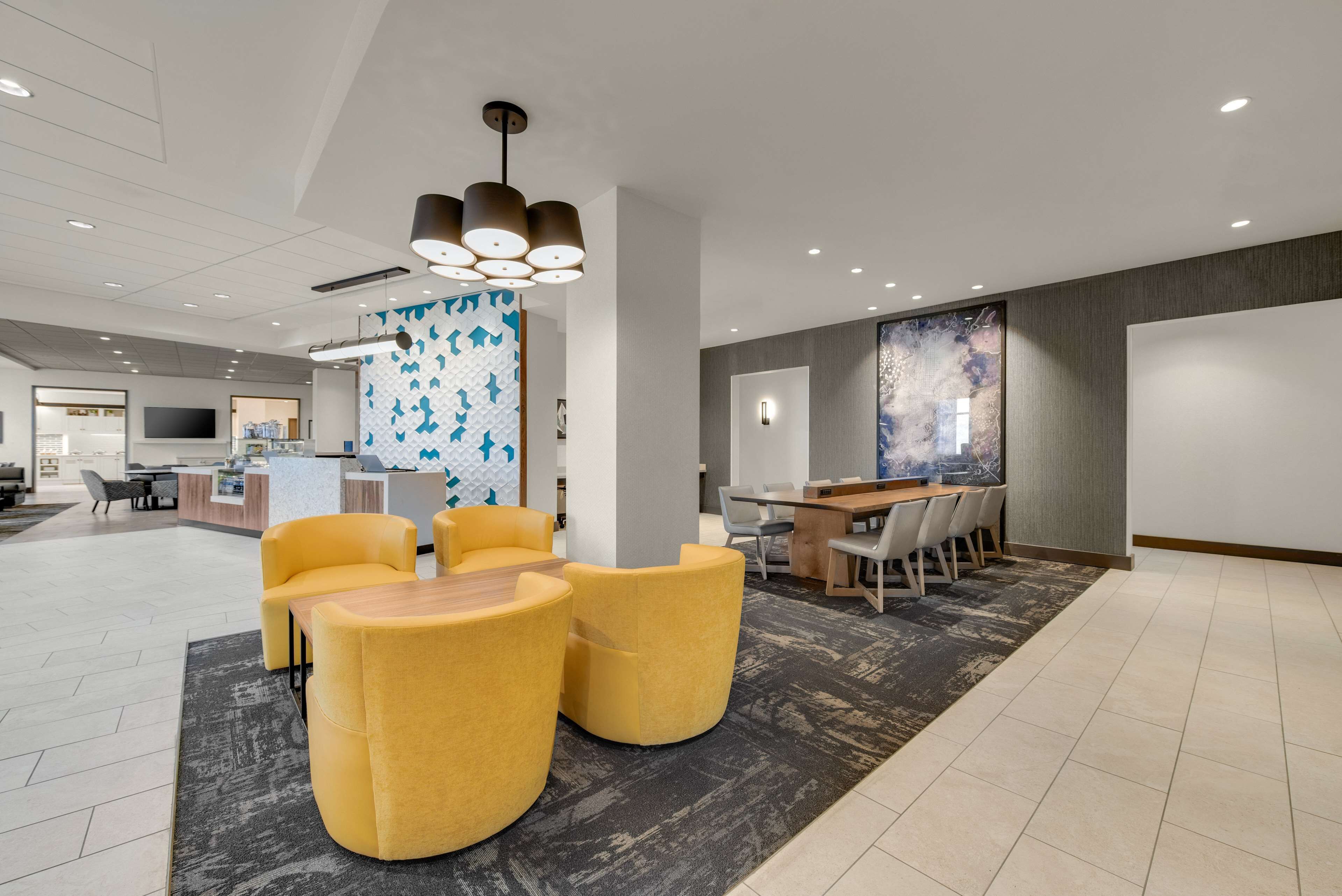 A modern lobby with yellow seating, a reception desk, and a large abstract mural.