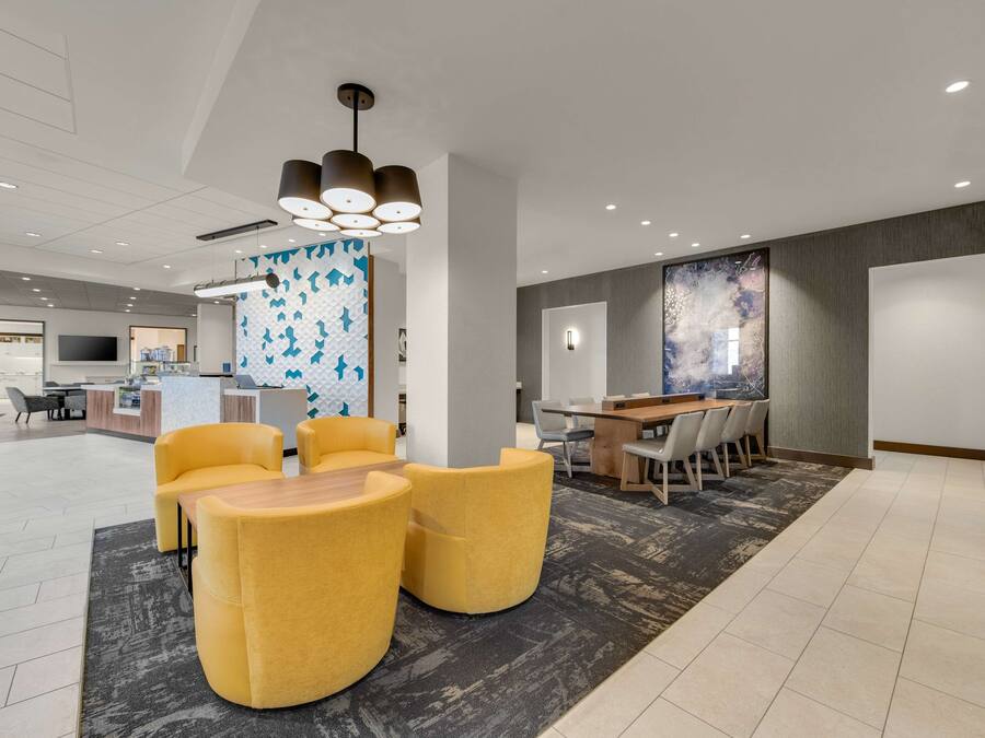 Eine moderne Lobby mit gelben Sitzgelegenheiten, einem Empfangstresen und einem großen abstrakten Wandbild.