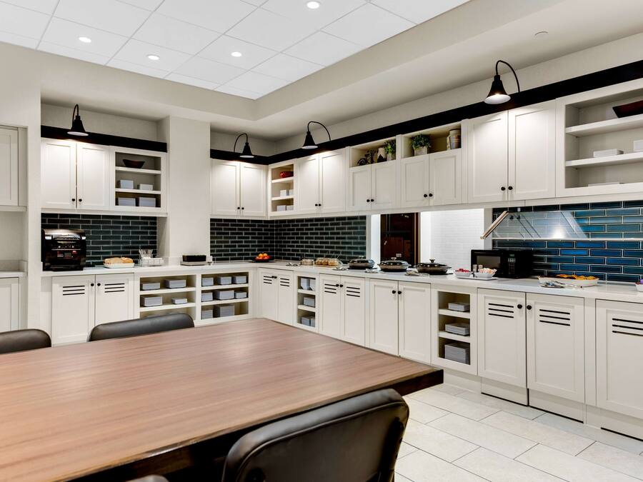 A modern kitchen with white cabinets, a wooden dining table, and black and white appliances.