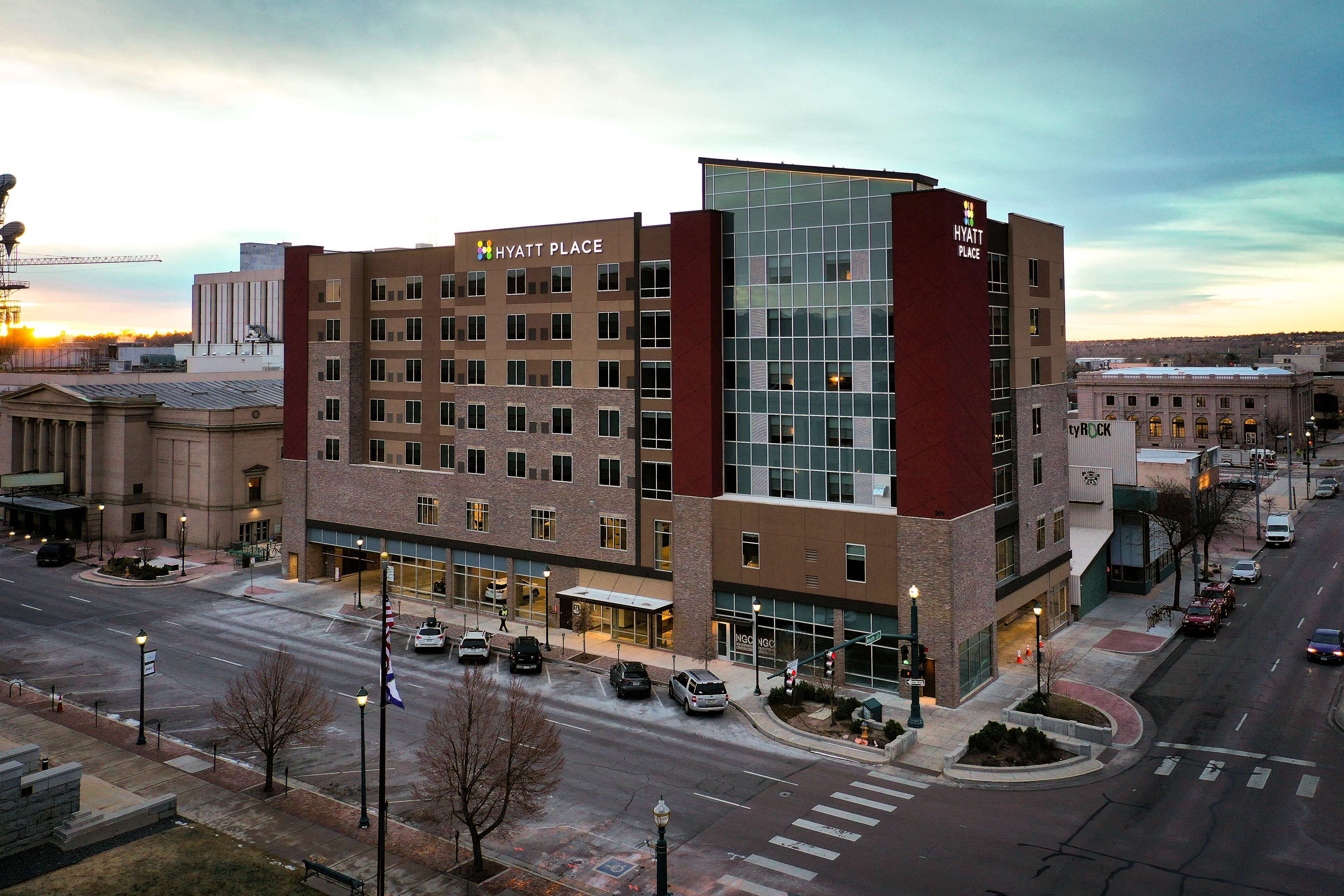 A multi-story hotel with a prominent glass facade, a brick base, and a sign reading "HYATT PLACE".