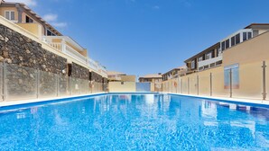 A swimming pool with a stone wall on one side and a building on the other. - Medano Beach (El Medano)