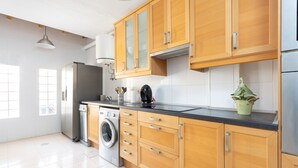 A modern kitchen with wooden cabinets, a stainless steel refrigerator, a washing machine, and a potted plant. - Medano Beach (El Medano)