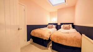 Een slaapkamer met twee bedden, een dakraam en een witte deur.