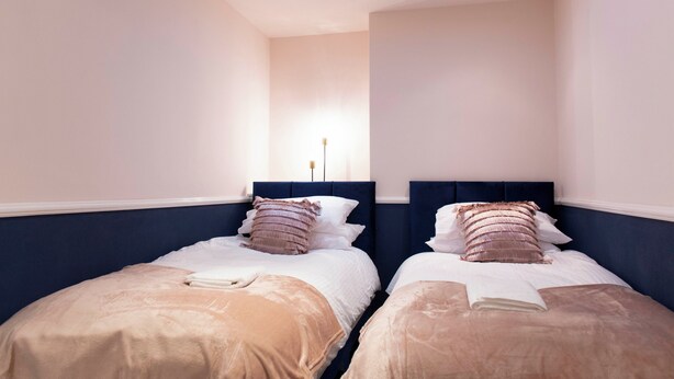 Une chambre avec deux lits, une lucarne et une lampe de chevet.