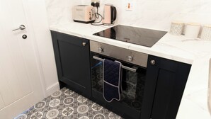 Een keuken met een zwarte oven, een inbouwmagnetron en een wit aanrecht.