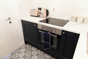 Une cuisine avec un four noir, un four à micro-ondes encastré et un plan de travail blanc.