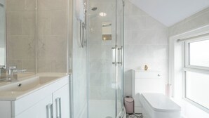 Une salle de bain moderne avec une douche à parois de verre, un lavabo blanc et des toilettes.
