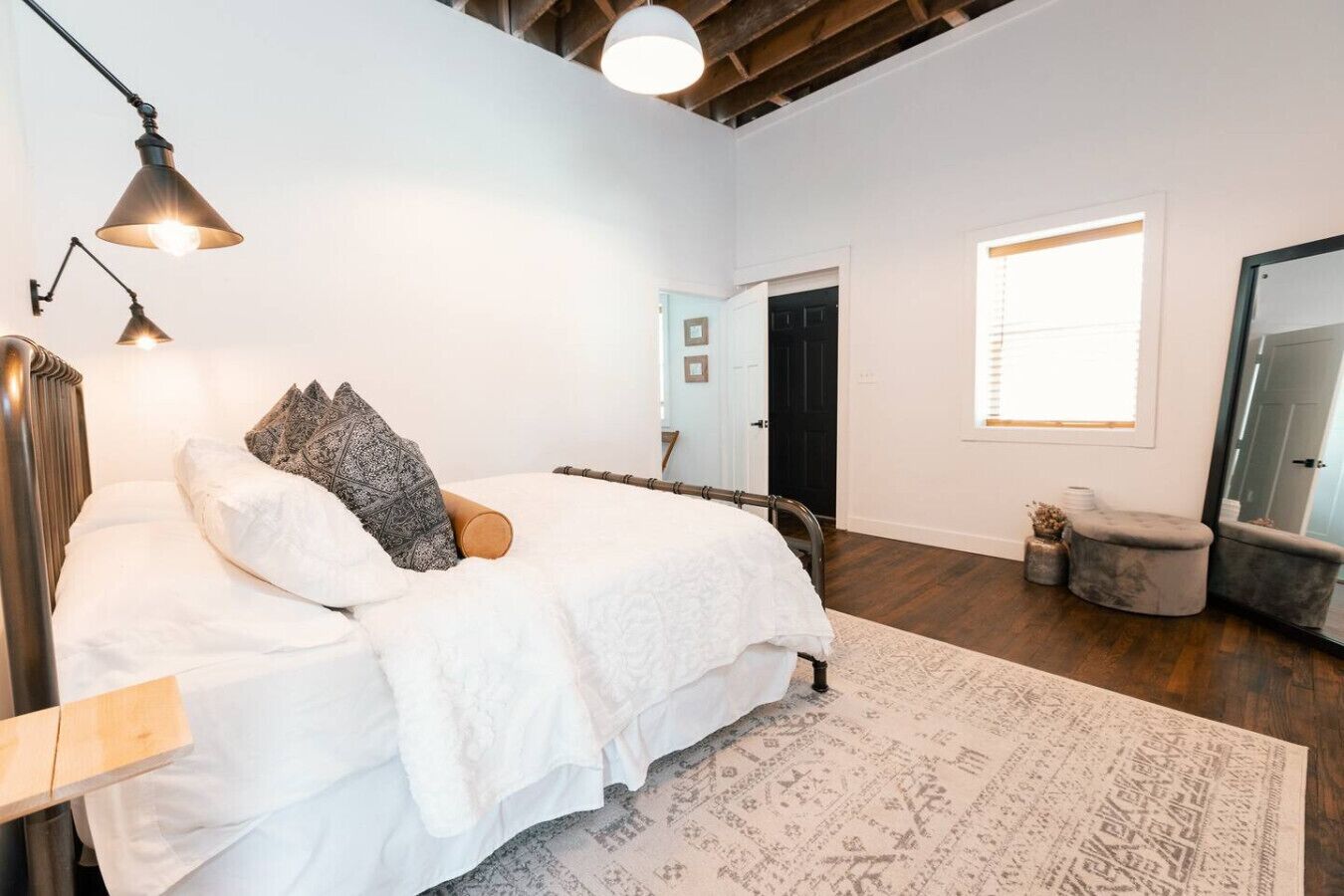 A bedroom with a bed, bedside lamps, a window, and a mirror.