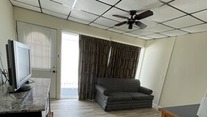 A room with a ceiling fan, a television, a sofa, and a dining table. - Searay Motel (Wildwood)