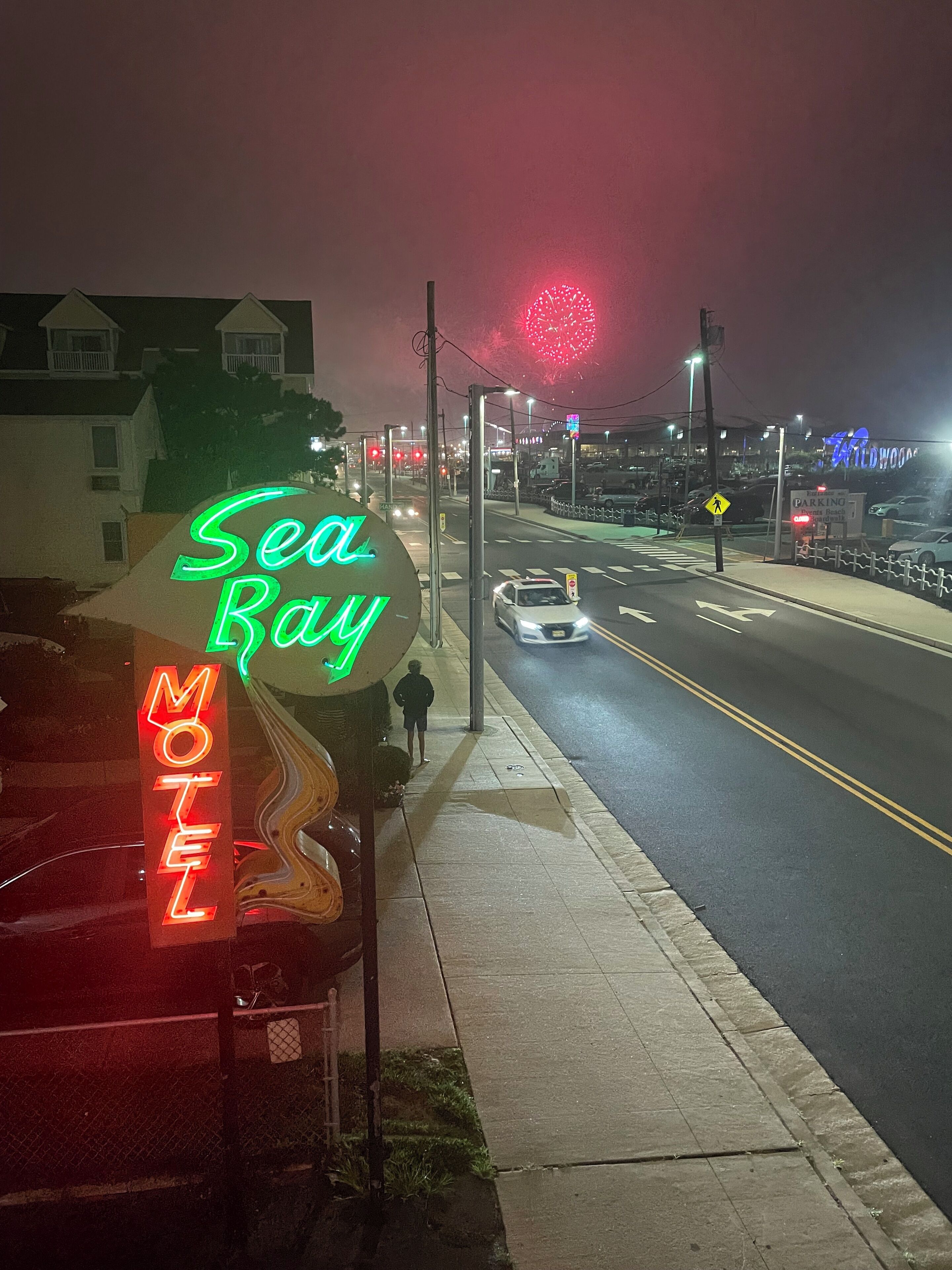 A motel sign with neon lights, a street with cars, and a pedestrian crossing.