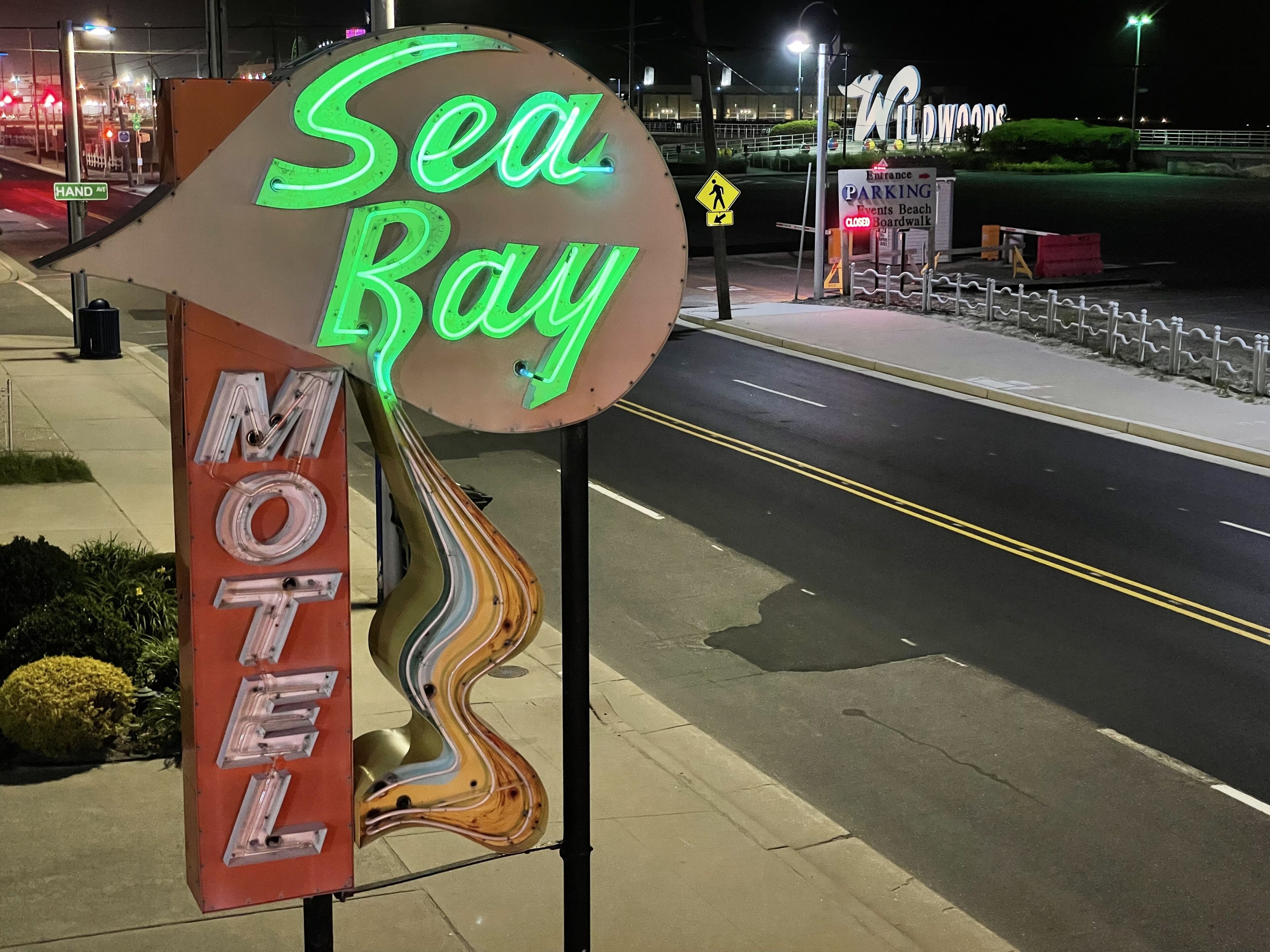 A neon sign for Sea Ray Motel with a unique design, featuring a road and a pedestrian crossing.