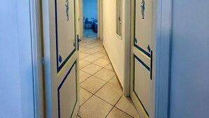 Un couloir avec deux portes, chacune ornée d’un motif décoratif. Le sol est carrelé et les murs sont peints dans une couleur claire.