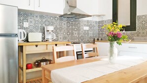 Eine Küche mit weißen Schränken, einem Edelstahl-Kühlschrank, einer Kaffeemaschine und einer Vase mit Blumen auf der Arbeitsplatte.