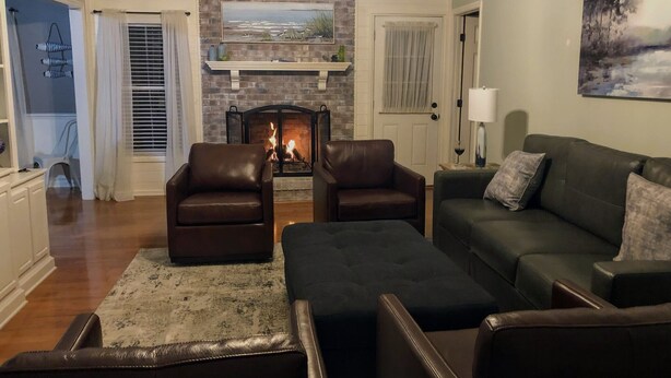 Uma sala de estar com lareira, poltronas de couro, sofá e um quadro na parede.