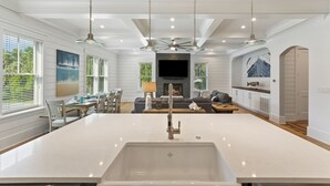 Une cuisine moderne dotée d’un îlot central, de luminaires suspendus et d’une cheminée.
