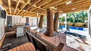 Une terrasse extérieure avec des poutres en bois, une balançoire et une piscine en arrière-plan.