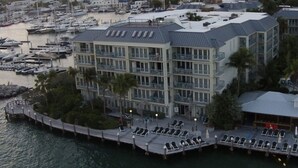 Un hôtel à plusieurs étages doté d’une piscine, de bateaux amarrés et d’une jetée avec des chaises longues.