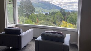 Quarto com dois sofás cinza e uma grande janela com vista para uma paisagem montanhosa.