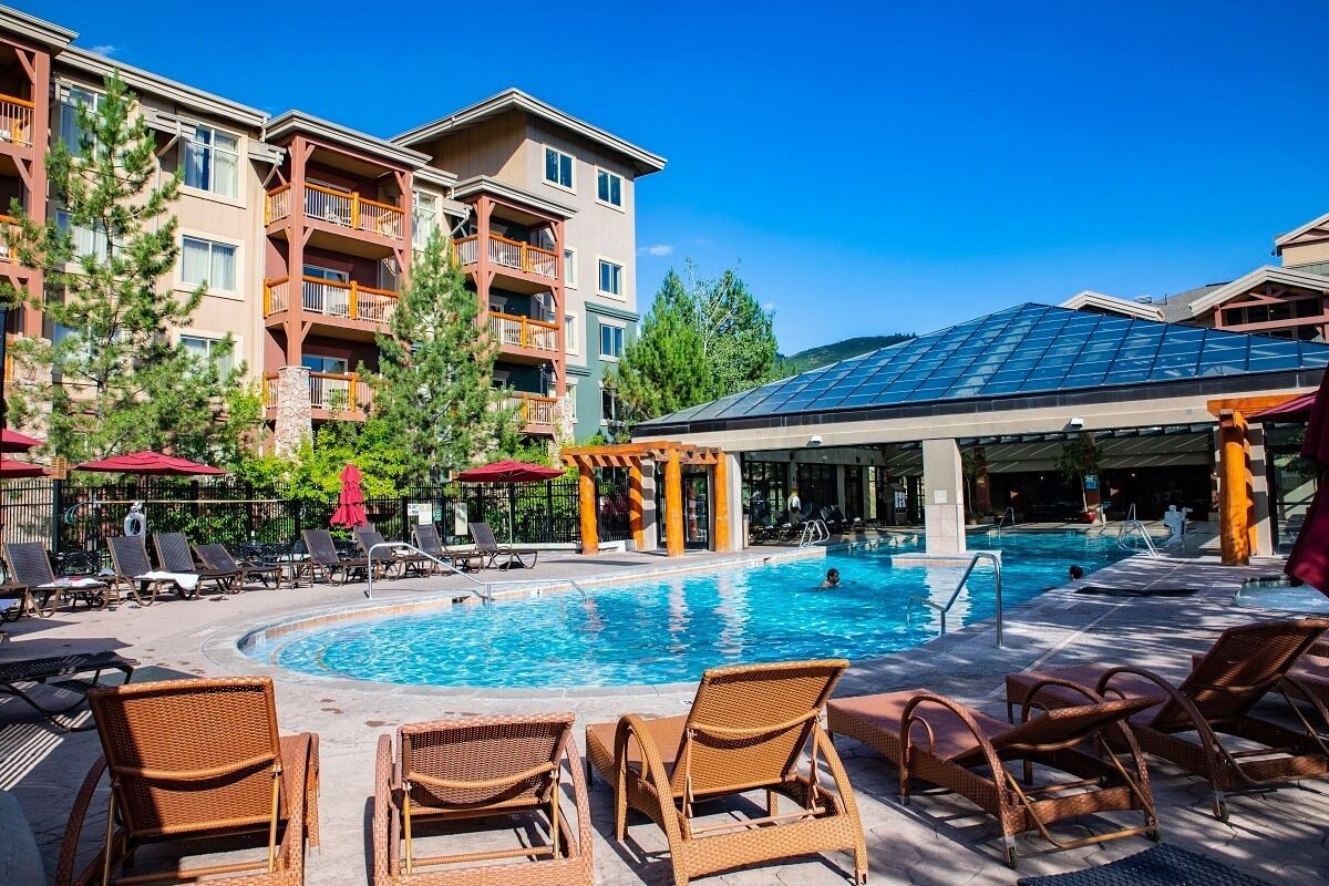 A hotel pool area with lounge chairs, a swimming pool, and a covered seating area.