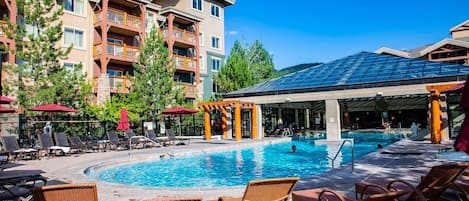 A hotel pool area with lounge chairs, a swimming pool, and a covered seating area.