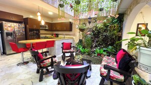 A modern kitchen with a central island, red bar stools, and a dining area with a table and chairs.