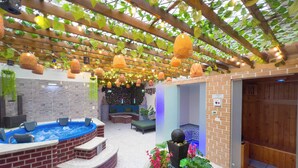 Een wellnessruimte met een jacuzzi, zitplaatsen en een decoratieve plantenopstelling.
