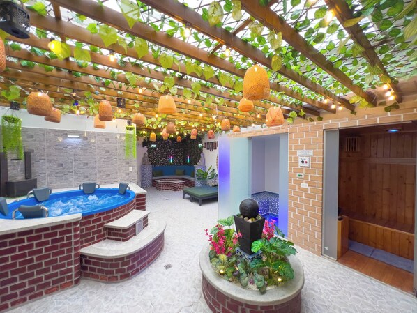 A spa area with a hot tub, seating, and a decorative plant arrangement.