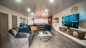 A modern living room with a sectional sofa, a coffee table, a flat-screen TV, and decorative wall art. - Modern Luxurious Apt With Spa Near Chipichape (Cali)