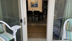 A room with a sliding glass door leading to a dining area with a table and chairs. - Wave Action!Condo on the Beach w/Umbrella Service next to famous Wanna Wanna Bar (South Padre Island)