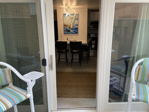 Una habitación con puerta corrediza de vidrio que da a un comedor con mesa y sillas.