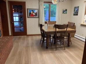 Ein Esszimmer mit Holztisch und -stĂŒhlen, einem Kamin aus Ziegelsteinen und ornamentalem Wandpapier.
