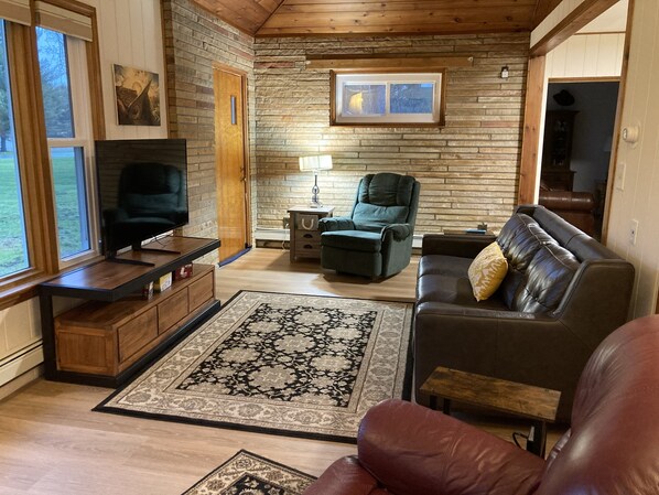 Una sala de estar con chimenea, televisión, sofá, sillón y alfombra.