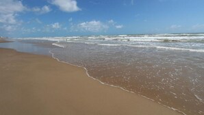 A beach with waves gently lapping onto the shore under a clear sky.