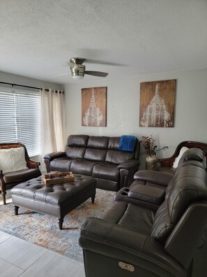 A living room with a brown leather sofa, a wooden coffee table, and a ceiling fan.