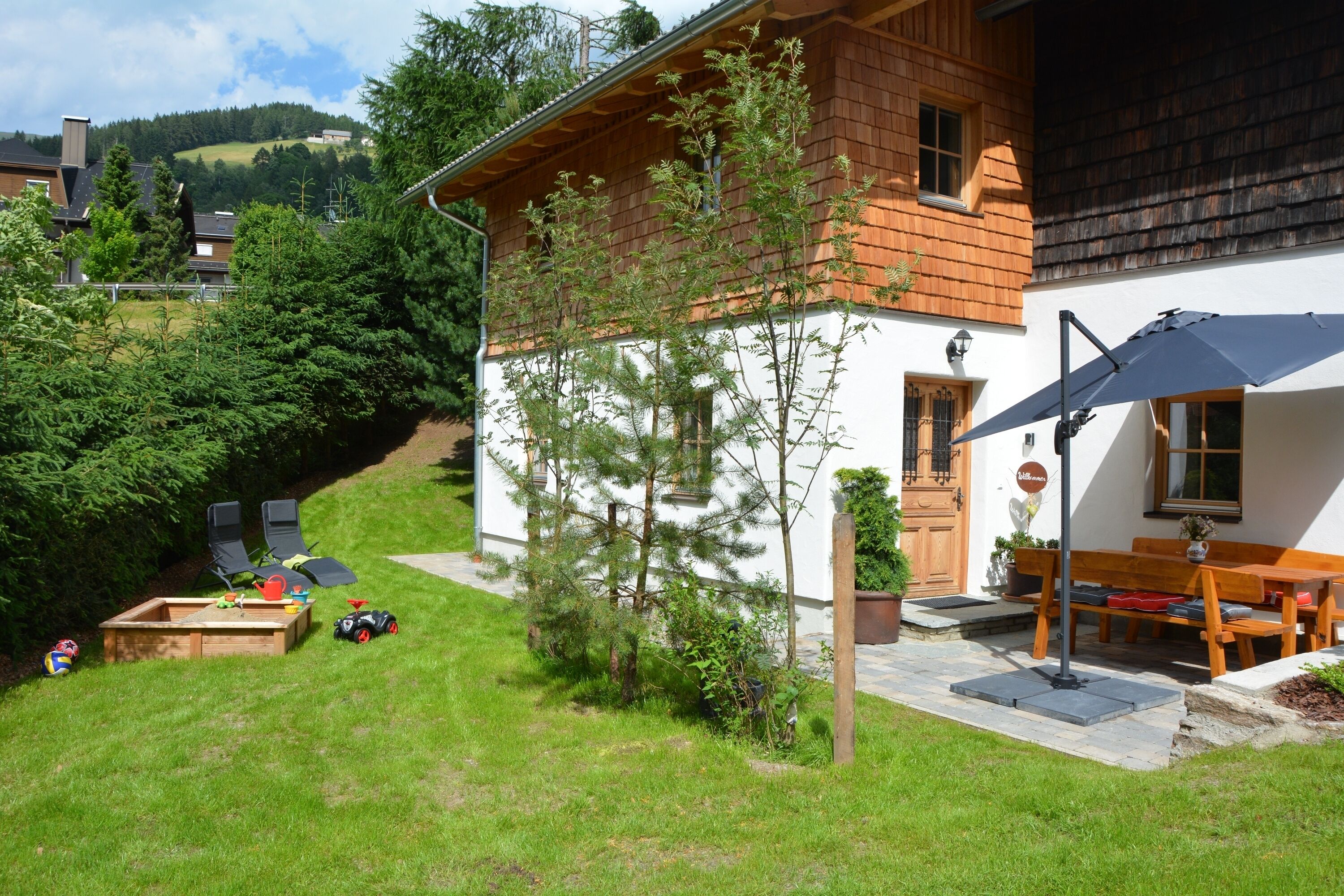 Una casa de madera con fachada blanca, una terraza de madera y un banco.