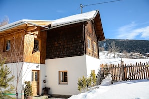 Une maison en bois avec un toit en pente, des murs extérieurs blancs et une clôture en bois.