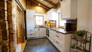 Uma cozinha moderna com armários brancos, teto de madeira e chão de azulejos pretos.