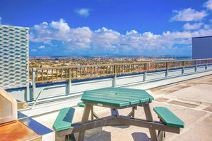 A rooftop terrace with a picnic table and a view of a cityscape.