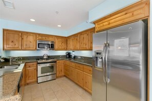 A kitchen with wooden cabinets, stainless steel appliances, a refrigerator, and a water dispenser. - Across from the beach, a/c, gated parking and pets (San Diego)