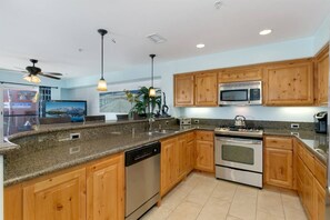 A modern kitchen with granite countertops, wooden cabinets, stainless steel appliances, and pendant lighting. - Across from the beach, a/c, gated parking and pets (San Diego)