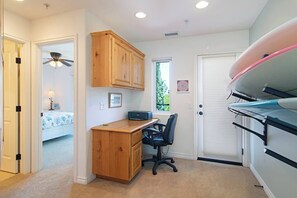 A bedroom with a bed, a desk, a chair, and a surfboard.