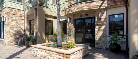 A building with a stone facade, a glass entrance, and a number '201-218' above the door.