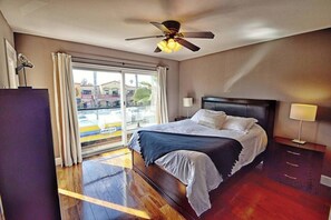 Une chambre d’hôtel avec un lit, un ventilateur de plafond, une fenêtre avec des rideaux et une vue sur l’extérieur.
