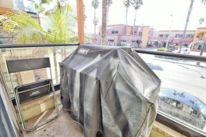 Un espace barbecue extérieur abrité, avec vue sur une rue et des immeubles.