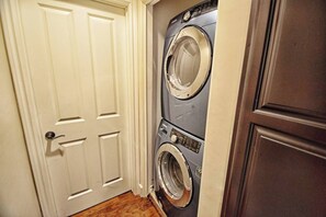 Une buanderie avec une porte et deux machines à laver superposées.