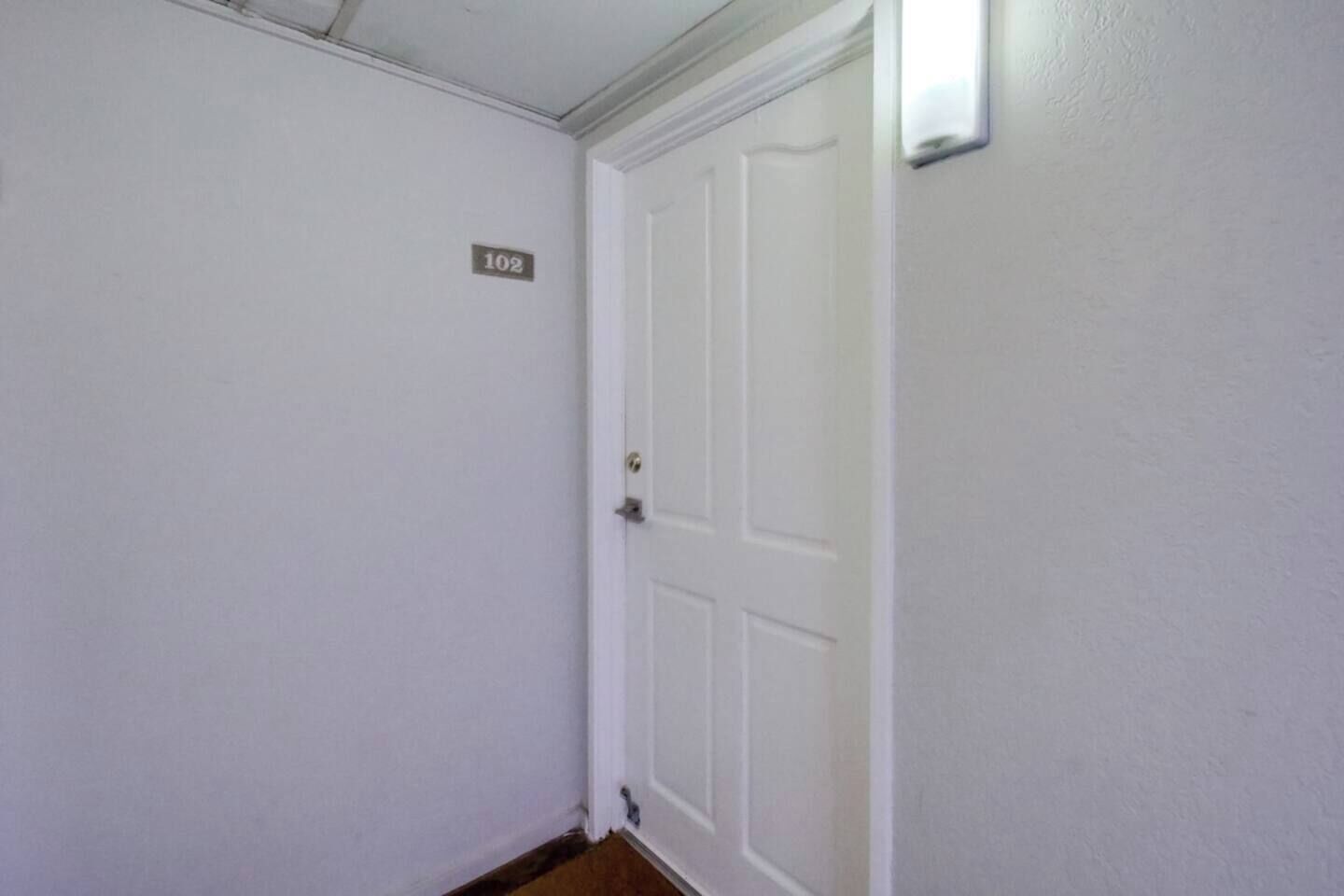 A white door with a number plate indicating room 102.