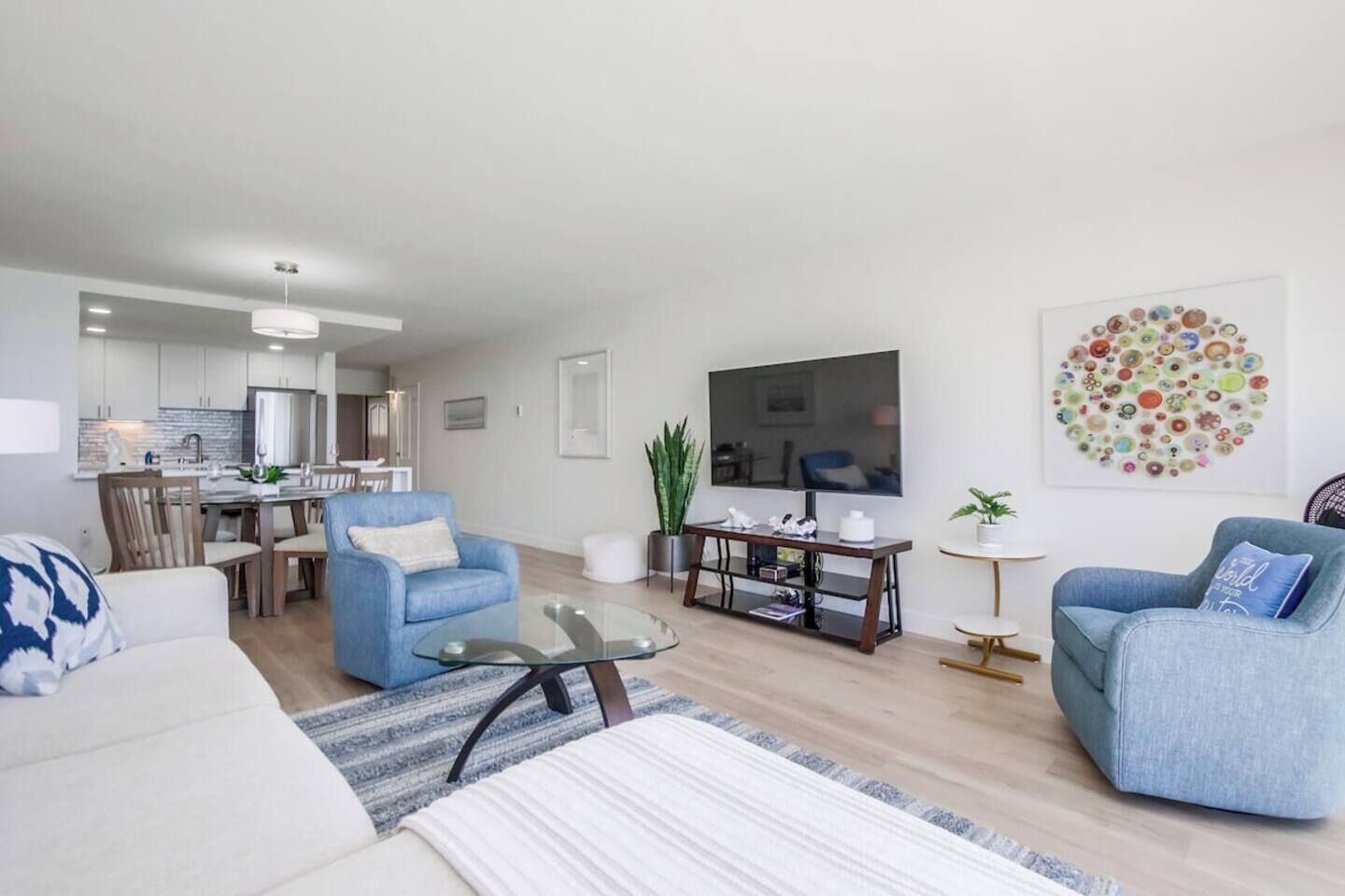A modern living room with a sofa, armchairs, a coffee table, and a TV.