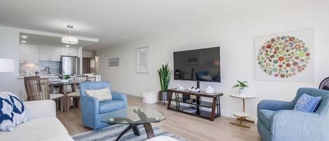 A modern living room with a sofa, armchairs, a coffee table, and a TV.