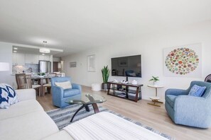 Un salon moderne avec un canapé, des fauteuils, une table basse et un téléviseur.